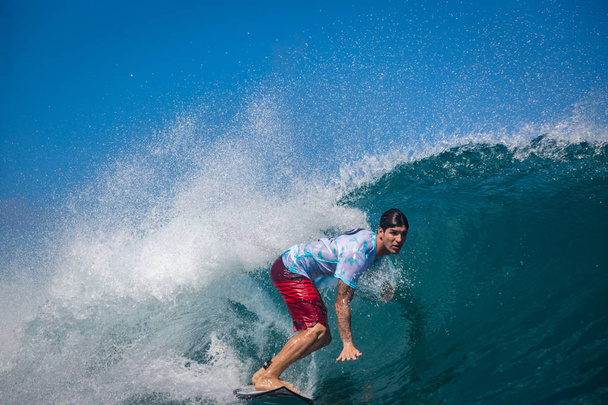 Indonesia, Bali, July 23 2016: A male surfer riding big blue ocean surfing wave, shot from water level - Fotografie, Obrázek