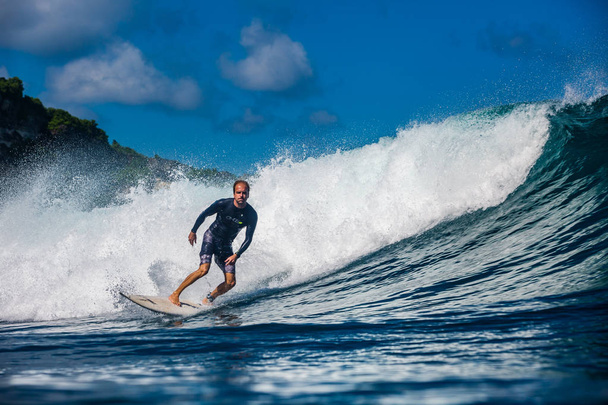 Indonesia, Bali, July 23 2016: A male surfer, Eduardo Ruaro, riding big blue ocean surfing wave, shot from water level - Foto, Imagem