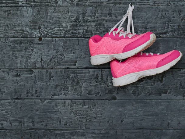 A pair of pink sport shoes on the background of a wooden wall. - Photo, Image