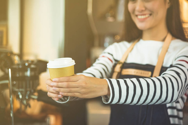 Happy barista serving a cup of coffee to customer  - 写真・画像