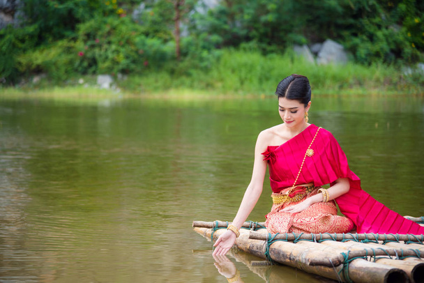 Krásná asijská žena thajské tradiční šaty sedí a dojemné vody - Fotografie, Obrázek