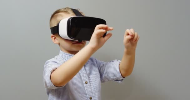 Portrait shot of the little boy using VR glasses and scrolling and zooming in front of him on the wall background. VR set. Inside - Záběry, video