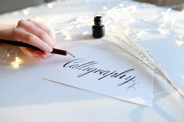 Il padrone femminile di scrittura di inchiostro scrive la parola su carta, sedendosi
 - Foto, immagini