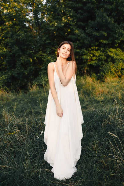 Giovane donna in abito lungo bianco in posa sulla natura
 - Foto, immagini