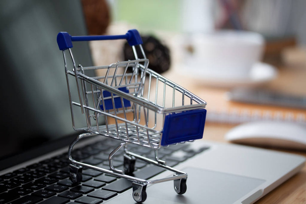 Mini shopping cart on computer laptop. Business concept. - 写真・画像
