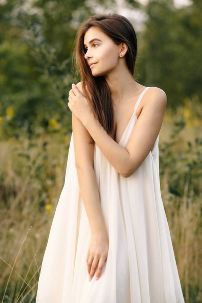 Young woman in long white dress posing  on nature - Fotó, kép