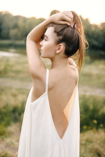 Young woman in long white dress posing  on nature - Foto, Bild