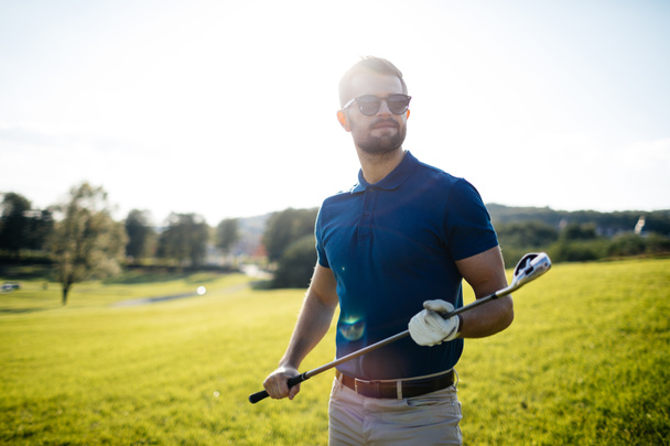 golf player hitting shot with club on course at beautiful morning with sun flare in background - Fotó, kép