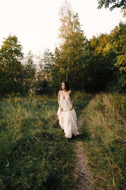 Young woman in long white dress posing  on nature - Foto, Imagem