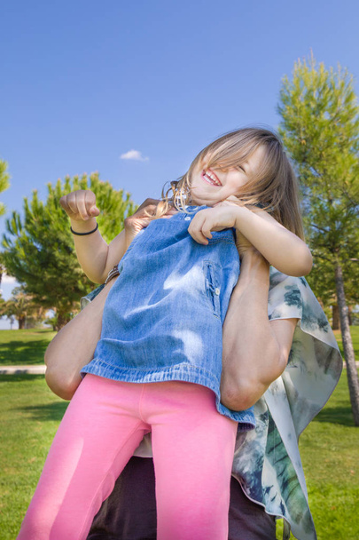 girl raised in mother hands laughing in the park - Foto, Bild