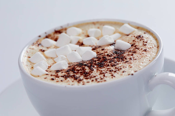 Tasse mit heißem Cappuccino und Marshmallow auf weißem Hintergrund  - Foto, Bild