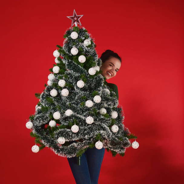 jeune femme avec arbre de Noël contre rouge
  - Photo, image