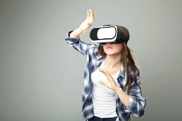 Young girl in virtual reality goggles on grey background - Фото, зображення