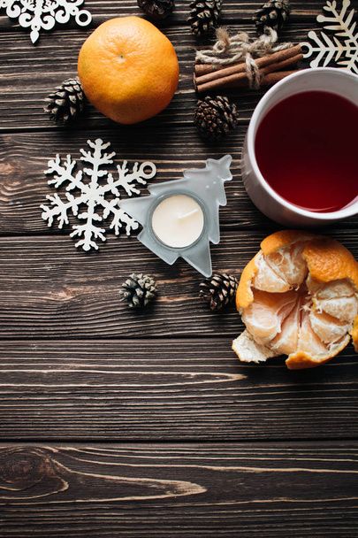 γκρο πλαν φρέσκα πορτοκάλια με φλιτζάνι τσάι για τη Χριστουγεννιάτικη διακόσμηση στο ξύλινο τραπέζι - Φωτογραφία, εικόνα