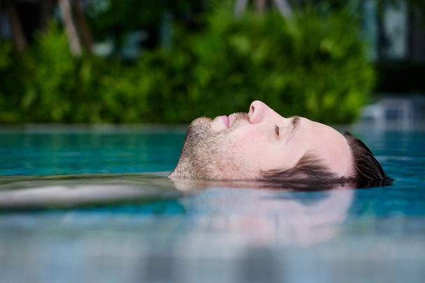 Content caucasian man in a swimming pool. - Zdjęcie, obraz