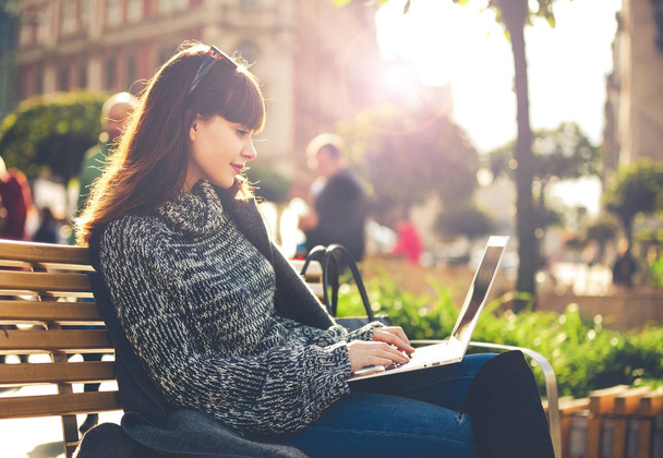Woman using laptop outdoor sitting in the city street, urban scene - Photo, image