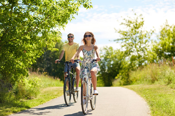 happy young couple riding bicycles in summer - Foto, Bild