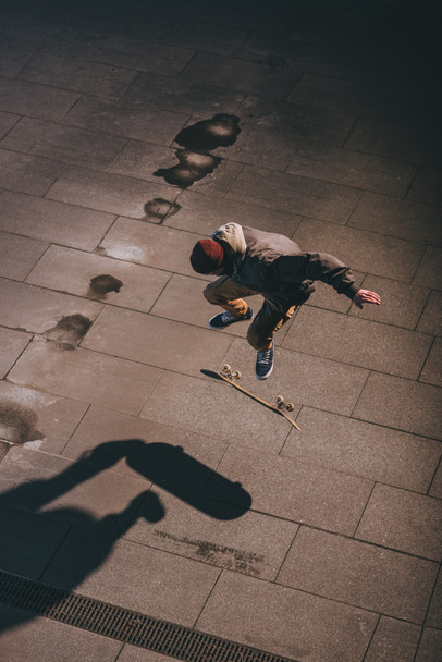 high angle view of skateboarder performing jump trick outdoors at late night - Photo, Image