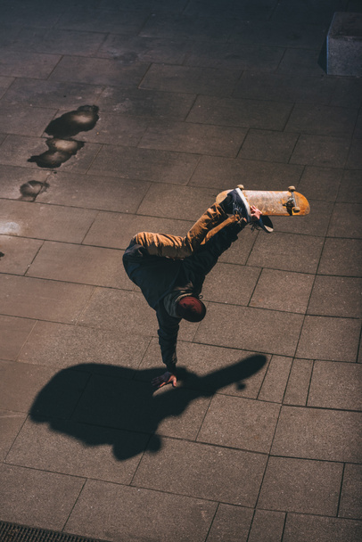 visão de alto ângulo do skatista realizando truque e de pé em uma mão
 - Foto, Imagem