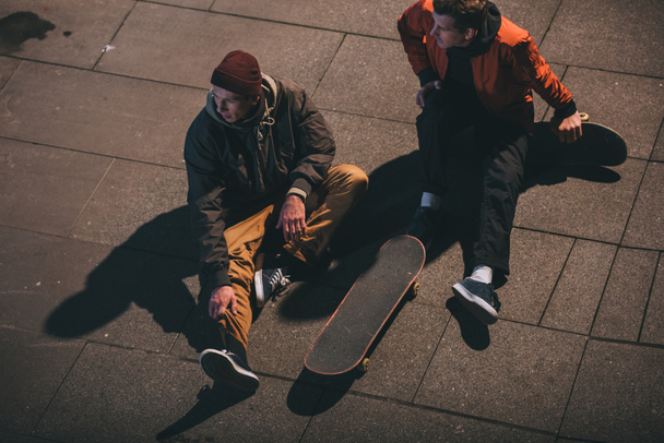 high angle view of skateboarders relaxing while sitting on floor - Zdjęcie, obraz