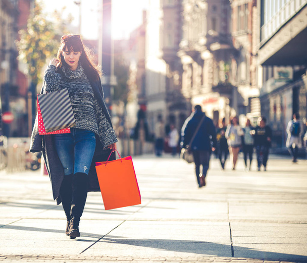Urban scene woman with shopping bags walking down the street - Фото, изображение