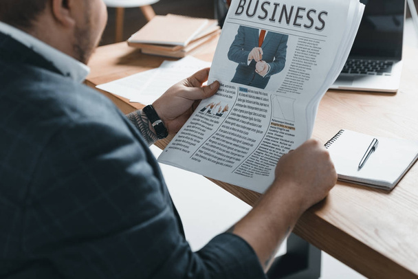 cropped view of overweight businessman reading business newspaper at workplace - Photo, Image