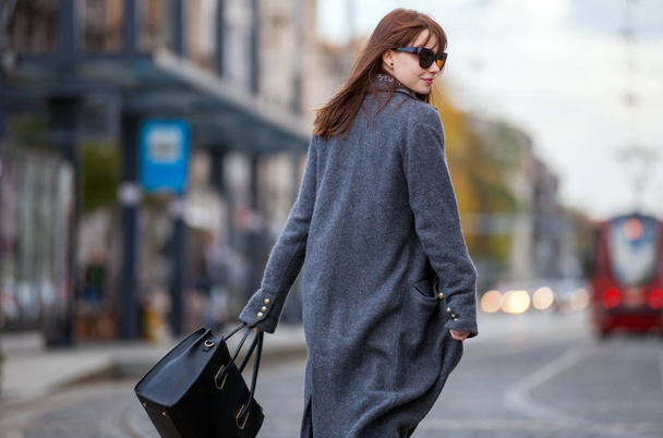 Trendy fashion woman in coat walking on the street, city scene - Фото, изображение