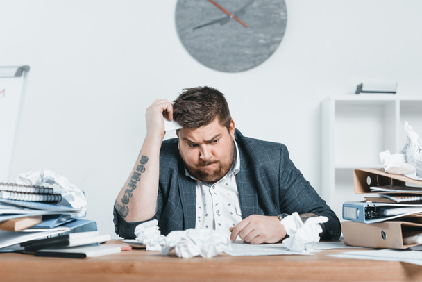 Verwirrter übergewichtiger Geschäftsmann im Anzug arbeitet im Büro mit Dokumenten - Foto, Bild