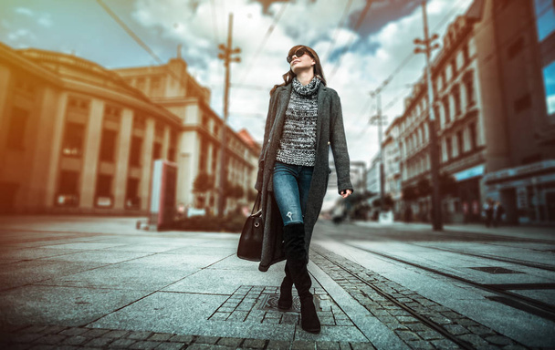 Casual fashion urban scene, trendy woman in coat walking on the street - Fotó, kép