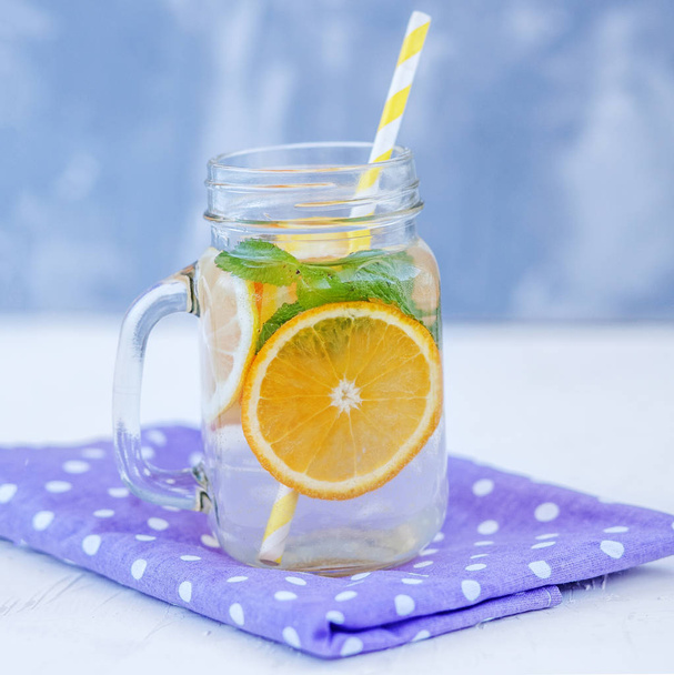 Δροσιστικό νερό αποτοξίνωσης με λεμόνι, πορτοκάλι και δυόσμο. Γυάλινο βάζο  - Φωτογραφία, εικόνα