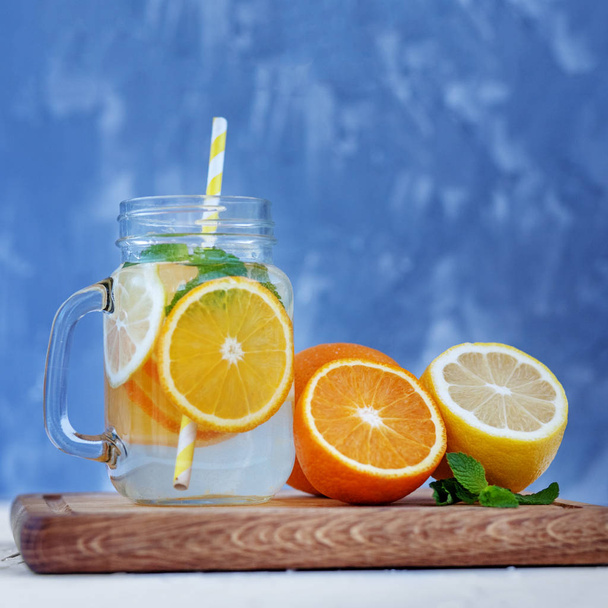 Verfrissende cocktail met citroen, sinaasappel en munt. Glazen pot  - Foto, afbeelding