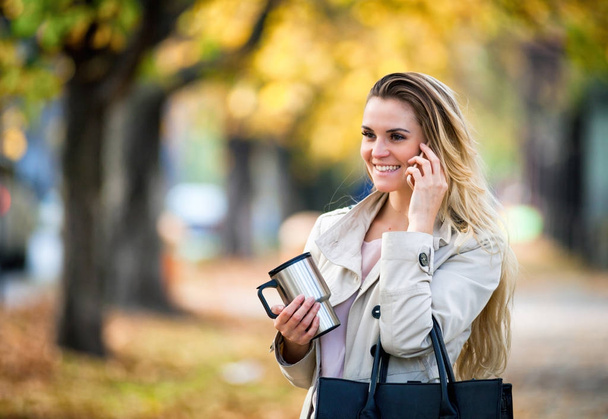 Beautiful woman talking smartphone walking colorful autumn street - Foto, Bild