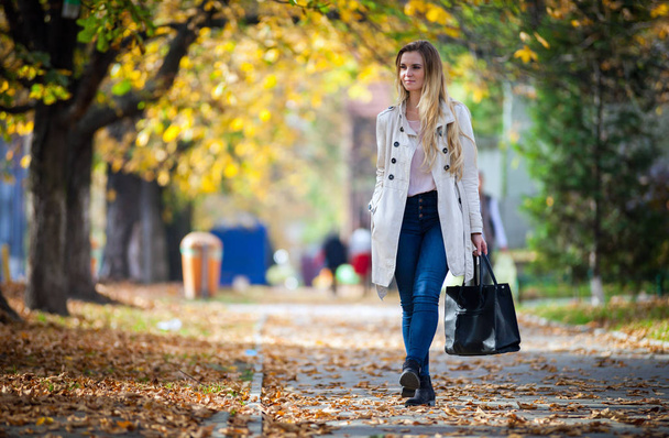 Smiling woman in coat walking on beautiful autumn street - Foto, Imagem