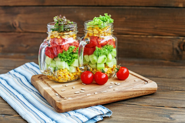 Ensalada de verduras en frascos de vidrio. Pepinos, tomates y maíz
.  - Foto, Imagen