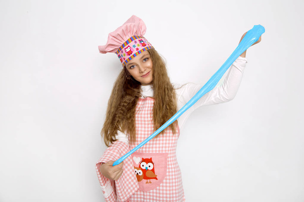 Cute funny girl with slime in the kitchen. The girl cooks and bakes her muffins, makes a cake and slime. - Photo, Image