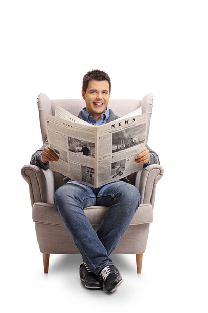 Young man with a newspaper sitting in an armchair - Foto, imagen