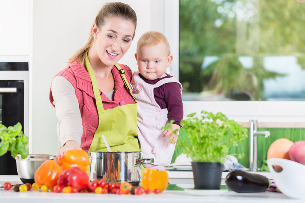 Matka, praca w kuchni podczas noszenia dziecka - Zdjęcie, obraz