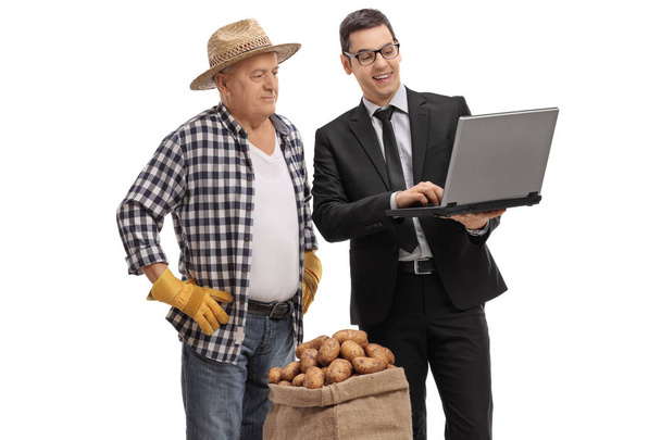 Businessman showing something on a laptop to a farmer  - Photo, image