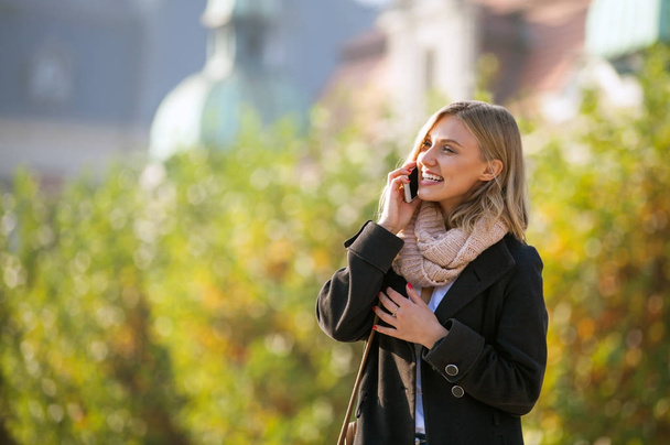 Woman talking on phone at the city street during autumn - Foto, Imagem
