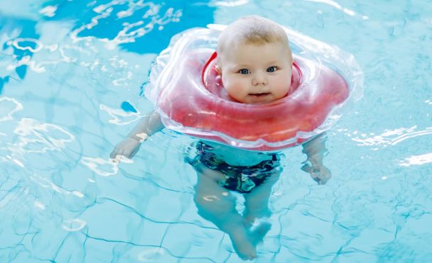 Lindo bebé pequeño aprendiendo a nadar con anillo de natación en una piscina cubierta
 - Foto, imagen
