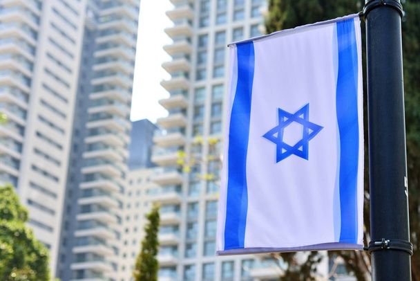 городской пейзаж с национальным израильским флагом и высотным отелем
 - Фото, изображение
