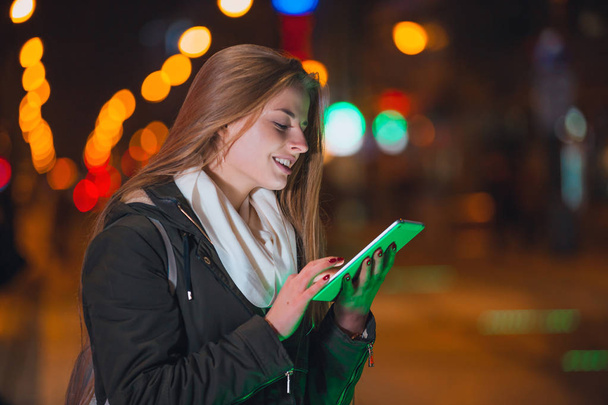 Beautiful woman using tablet in the city at night - Foto, afbeelding