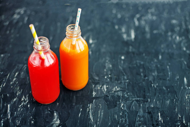 Strawberry and orange juice. The glass bottle. Dark background.  - Photo, image