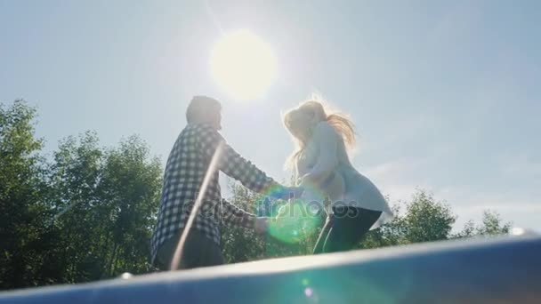 トランポリンで高くジャンプ友達の陽気なカップルは。空に太陽を閉じる。スローモーション映像 - 映像、動画