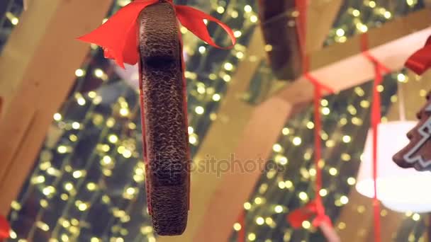Souvenir cookies decorated with winter ornament, hunging retail trade at christmas fair on street. new year street decorations gingerbread and glowing garlands - Footage, Video