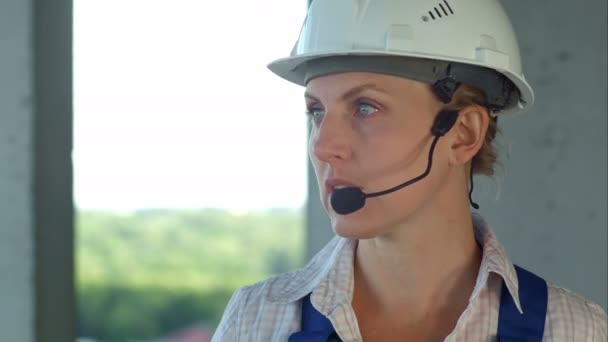 Γυναίκα οικοδόμος μηχανικός εξετάζει ένα σχέδιο για τη νέα κατασκευή και μιλώντας μέσω μικροφώνου - Πλάνα, βίντεο