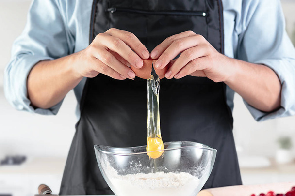 ein Koch mit Eiern in einer rustikalen Küche vor dem Hintergrund von Männerhänden - Foto, Bild