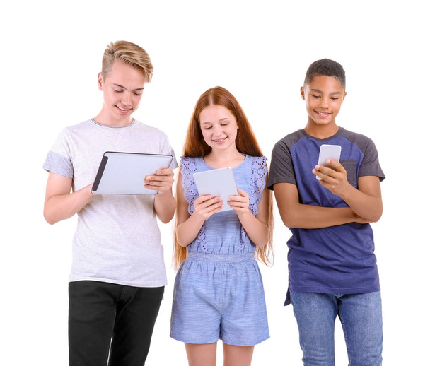 Schattige tieners met Tablet PC's en mobiele telefoon op witte achtergrond - Foto, afbeelding