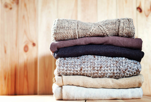 Knit уютный свитер сложенный в кучу на деревянном фоне.
 - Фото, изображение