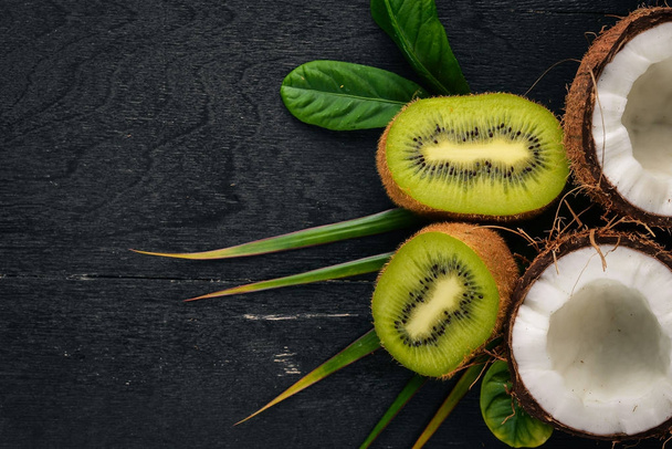 Coconuts and kiwi on a wooden background. Tropical fruits and nuts. Top view. Free space for text. - Foto, immagini